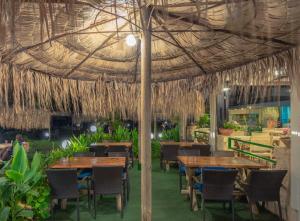 a restaurant with tables and chairs under a straw umbrella at Erato Hotel Adults Only by Smile Hotels in Platanias