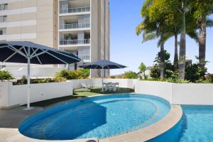 a swimming pool with an umbrella next to a building at The Dalgety Apartments in Townsville