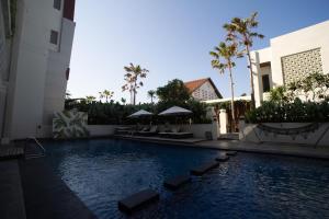 a swimming pool in the middle of a building with palm trees at Luminor Hotel Banyuwangi By WH in Banyuwangi
