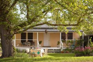 a yellow house with a table and chairs in the yard at Bird House in Kyneton