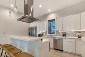 a kitchen with white cabinets and a large island with stools at Bienville Villas: Brand New 4BR in New Orleans