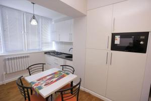 a kitchen with white cabinets and a table with chairs at Newly Renovated Modern 2 Bed Apt Near Gur-e-Amir in Samarkand