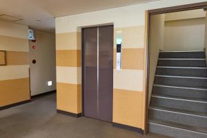 un pasillo con escaleras y ascensores en un edificio en Tabist Kanko Business Hotel Matsuyama Hida Takayama, en Takayama