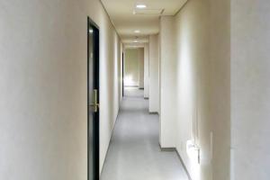 un pasillo con paredes blancas y una puerta negra en Tabist Kanko Business Hotel Matsuyama Hida Takayama, en Takayama