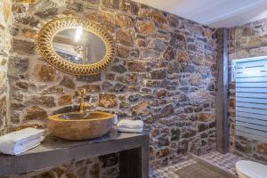 Baño de piedra con lavabo y espejo en Perachori Boutique Studios en Anogia