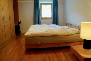 una camera da letto con un letto con tende blu e una finestra di Chasa Anna a Scuol