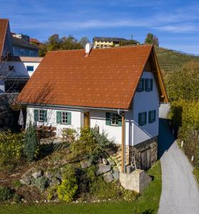 a white house with an orange roof on a hill at Kellerstöckl Goigner in Kitzeck im Sausal