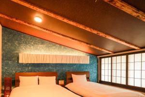 two beds in a room with two windows at Yurakuan - Awagami Residence Inn in Kyoto