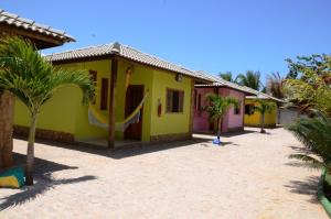 een geel huis met een hangmat ervoor bij Pousada Vila Arco-Iris in Porto de Sauipe