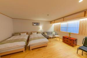 1 dormitorio con 2 camas, sofá y mesa en YADOYA Uguisu, en Tokio