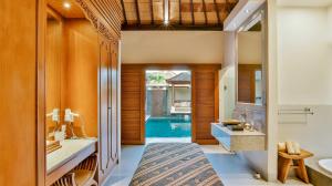 ein Badezimmer mit einem Bett, einem Waschbecken und einem Spiegel in der Unterkunft DISINI Luxury Spa Villas-CHSE Certified in Seminyak