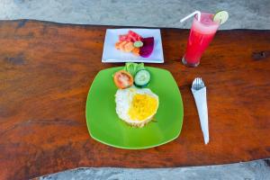 a green plate with eggs and fruit and a drink at The Dewi Sun Sun Nusa Penida in Nusa Penida