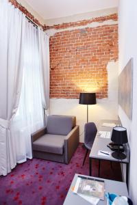 ein Wohnzimmer mit einem Stuhl und einer Ziegelwand in der Unterkunft Koszary Arche Hotel in Góra Kalwaria