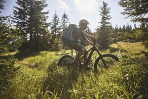 eine Person, die Fahrrad im Gras reitet in der Unterkunft Lake Peak Apartments, Ribniško Pohorje in Ribnica na Pohorju