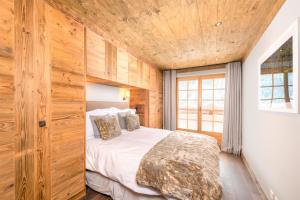 a bedroom with a bed and a wooden wall at Chalet Ourson Brun by Mrs Miggins in Grimentz