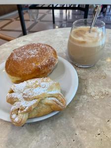 dos donuts en un plato junto a una taza de café en Guest House Margherita, en Albignasego