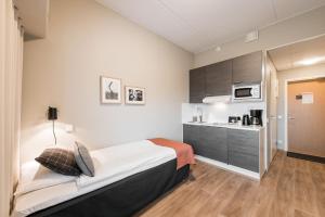 a bedroom with a bed and a kitchen at Forenom Aparthotel Espoo Leppävaara in Espoo