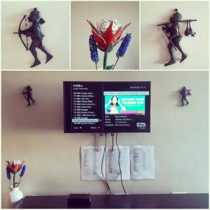 a computer monitor on a wall with some flowers at Field's Rest: The Apartment in Port Elizabeth