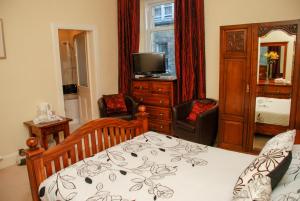 um quarto com uma cama, uma cómoda e uma televisão em BELL CRAIG GUEST HOUSE em Fife