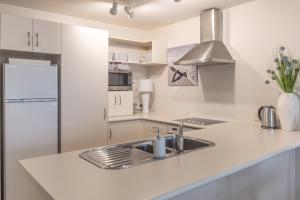 a white kitchen with a sink and a refrigerator at Beach Break Escape 226 in Mount Maunganui