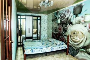 Zimmer mit einem Bett vor einer Wand mit Blumen in der Unterkunft Апартаменты Зварыгина, 16 in Rakitnyy