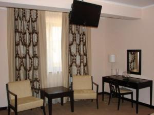 a living room with a table and chairs and a television at Griff Hotel Zalau in Zalău