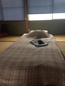 a bed with a comforter on top of it at Guest House Mitsuka in Shishikui