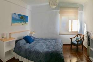 a bedroom with a bed and a chair and a window at Piso en San Roque, centro neurálgico del Campo de Gibraltar in San Roque