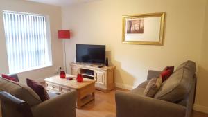 a living room with two chairs and a flat screen tv at Pageant Lodge in Telford