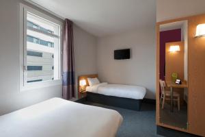 タッサン・ラ・ドゥミ・リュンヌにあるB&B HOTEL Lyon Ouest Tassinのベッド2台と窓が備わるホテルルームです。