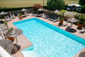 une grande piscine avec des chaises et des parasols dans l'établissement Camping Saint Michel, à Courtils