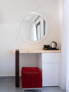 a table with a mirror and a red stool at Eva Mare Hotel & Suites - Adults only in Agia Pelagia