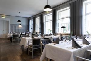 a restaurant with white tables and chairs and windows at Tyringe Kurhotell in Tyringe