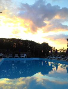 a pool with chairs and a sunset in the background at Residence La Carruba in Diano Marina