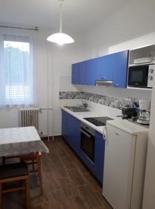 a kitchen with blue cabinets and a white stove top oven at Sport Apartman Tapolca in Tapolca