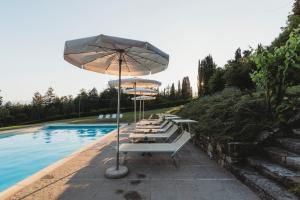 a row of chairs with umbrellas next to a pool at Appartamenti Catarsena in Banzena