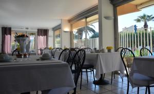 a dining room with two tables and chairs and windows at Hotel Albizzia in Valras-Plage