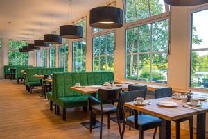 un restaurante con mesas, sillas verdes y ventanas en Lake House Plön, en Plön