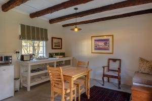 een keuken met een tafel en stoelen in een kamer bij Honeyrock Cottages in Kleinmond