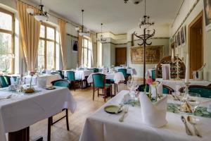 uma sala de jantar com mesas e cadeiras brancas em Hotel Jagdschloss Letzlingen em Letzlingen