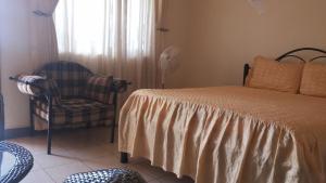 ein Schlafzimmer mit einem Bett, einem Stuhl und einem Fenster in der Unterkunft Westcliff Hotel in Lira