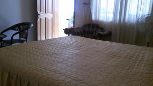 ein weißes Bett in einem Zimmer mit Stühlen und einem Fenster in der Unterkunft Westcliff Hotel in Lira