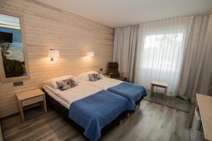 a hotel room with a bed, chair, and nightstand at Hotel Ivalo in Ivalo