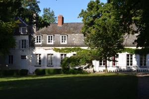 Una casa blanca con un árbol delante. en B&B La tour blanche en Forest-Montiers