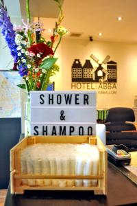 a sign that says shower and shampoo on a table with flowers at Hotel Abba in Amsterdam