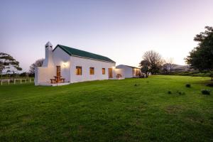 a small white church on a grass field at Honeyrock Cottages in Kleinmond