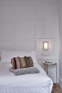 ein weißes Bett mit einem Kissen und einem Beistelltisch in der Unterkunft Cosmo Hotel Boutique in Valencia