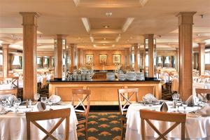 un restaurante con mesas y sillas blancas y un bar en Jaz Crown Jubilee Nile Cruise - Every Thursday from Luxor for 07 & 04 Nights - Every MondayFrom Aswan for 03 Nights, en Luxor