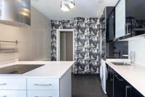a kitchen with white cabinets and a black and white wallpaper at Bilbao Volantin II with jacuzzi by Aston Rentals in Bilbao