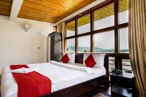 a bed with red pillows in a room with a window at Silver Brook Resort Mylliem Upper Shillong in Shillong